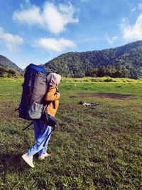 Full length of woman with backpack on field