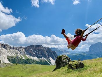 Girl on swing at mountain against sky