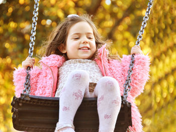 Close-up of cute girl on swing at playground