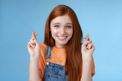 Woman with fingers crossed against blue background