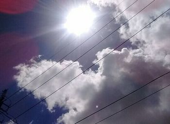 Low angle view of power lines against cloudy sky