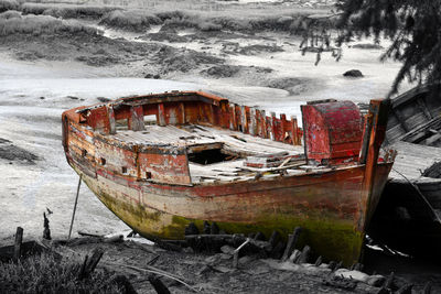 Abandoned boat moored at shore during winter