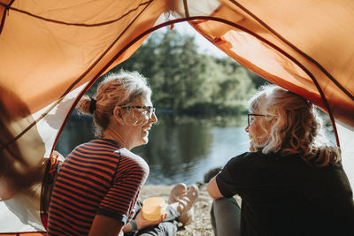 Two senior women sitting in tent at campsite