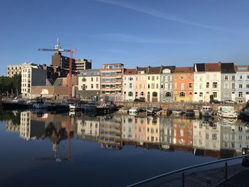 Reflection of buildings in river against blue sky