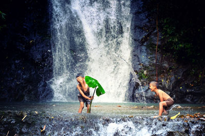Full length of shirtless man splashing water