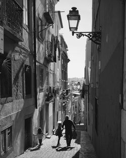 People walking on narrow street amidst buildings in city