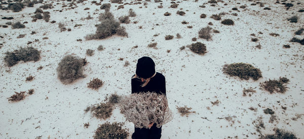 Fashion photo. girl in black clothes in the desert with a bouquet dead branches