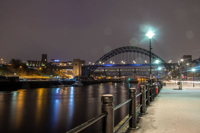 Illuminated bridge over river at night