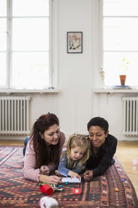 Girl and lesbian couple using digital tablet in living room