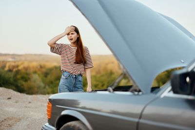 Side view of smiling young woman using mobile phone in car