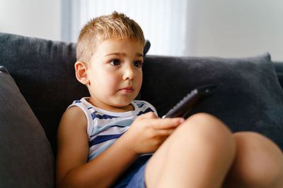 Boy sitting on sofa at home