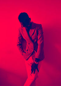 Young man standing against red background