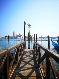 Pier over sea against clear blue sky