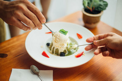 Midsection of man holding ice cream on table