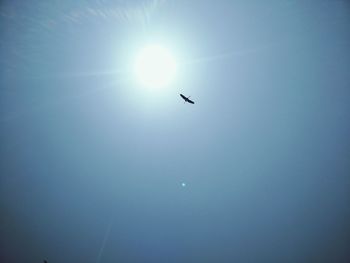 Low angle view of airplane flying against clear blue sky