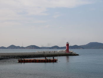 Lighthouse by sea against sky