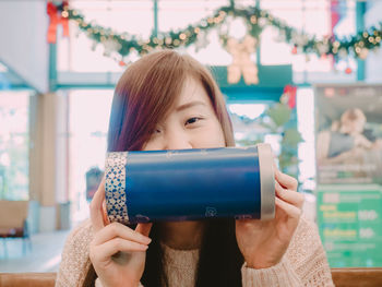 Portrait of woman holding container in cafe