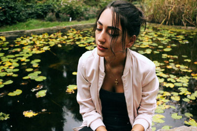 Young woman with leaves in lake during autumn