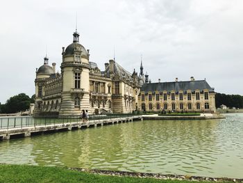 View of building by river against sky