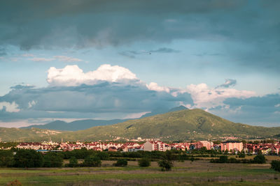 Scenic view of townscape and mountains against sky