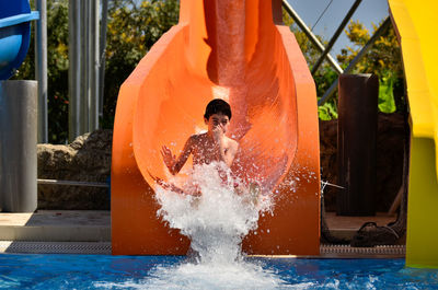 Boy sliding in pool at water park