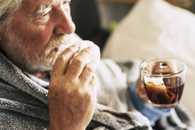 Close-up of senior man drinking beer at home