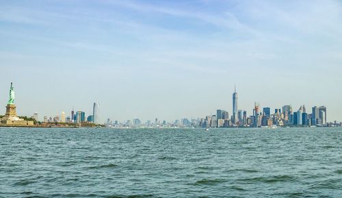 Sea by buildings against sky in city