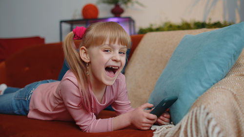 Young woman using phone while sitting on sofa at home