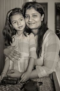 Portrait of mother and daughter sitting at home