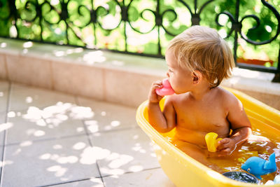 Girl with toys sitting in bathtub