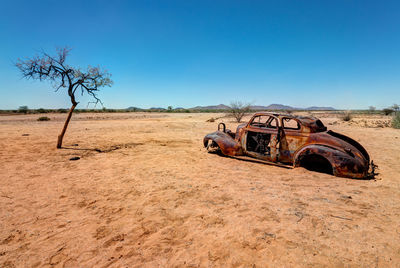 Abandoned truck on field against clear blue sky