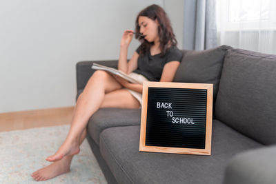 Young woman using laptop while sitting on sofa at home