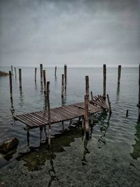 Wooden posts on beach against sky