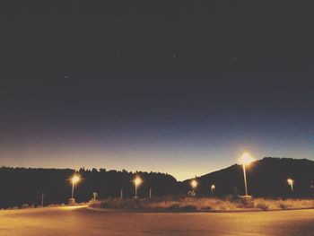 Illuminated street lights against clear sky at night