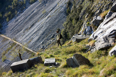 Search of treasures with metal detector in a steep path between peak of the rocky green mountains 