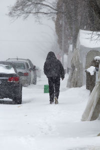Rear view of person walking on snow covered landscape