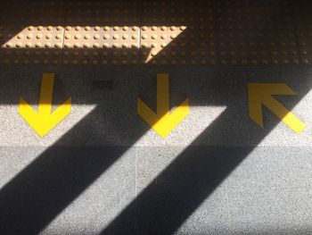 High angle view of arrow sign on tiled floor