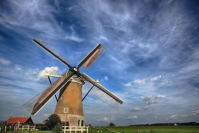Low angle view of wind turbine against cloudy sky