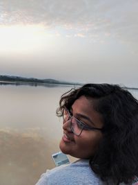 Portrait of woman by sea against sky during sunset