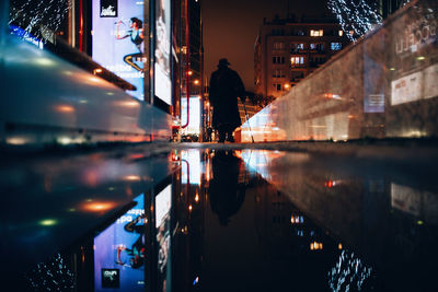 Reflection of illuminated buildings in puddle at night