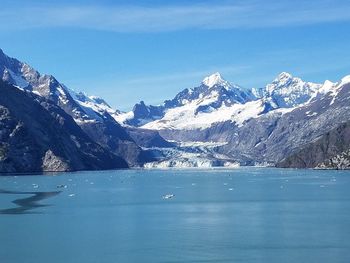 Scenic view of lake and snowcapped mountains against blue sky