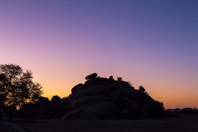 Silhouette rocks against clear sky during sunset