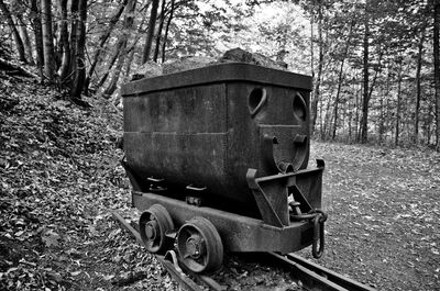 Abandoned vehicle on field by trees in forest