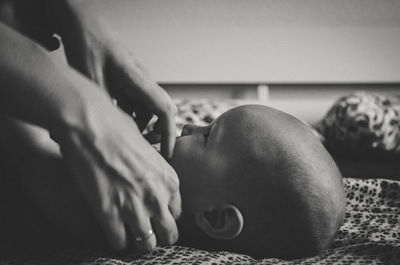 Cropped hands of parent touching baby on bed at home