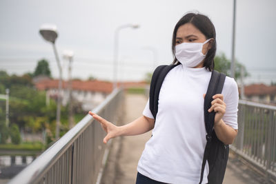 Portrait of young woman standing against railing