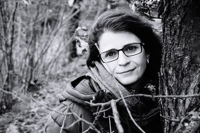 Portrait of smiling woman by tree trunk