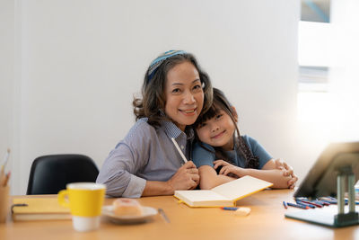 Portrait of smiling woman with granddaughter at home
