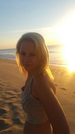 Portrait of woman at beach against sky during sunset