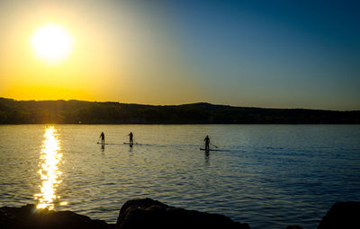 Silhouette of three people paddling