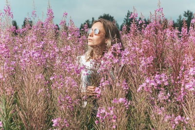 Woman standing on pink flowering plants on field